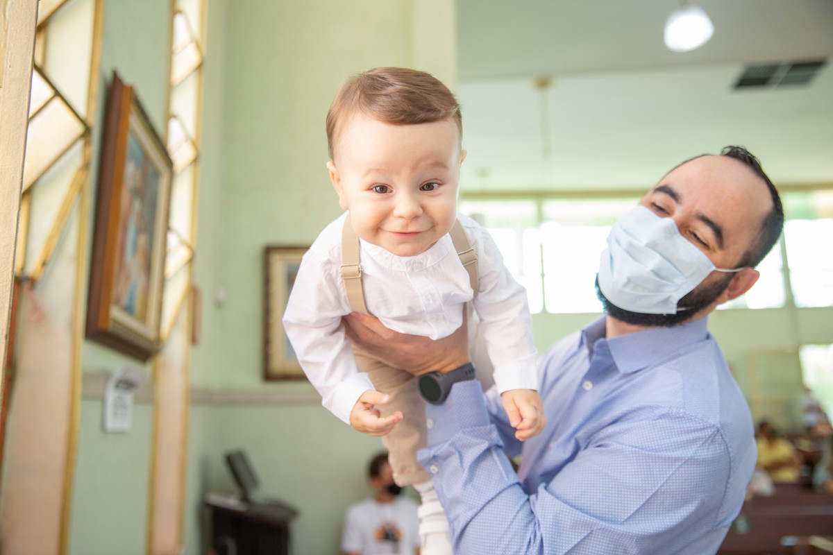 Menino voando nos braços do pai no batizado