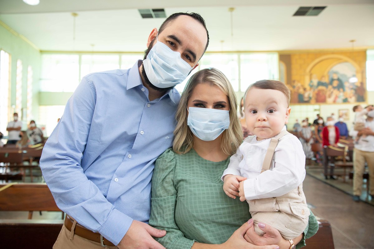 mae pai e menino bebe no colo batizado