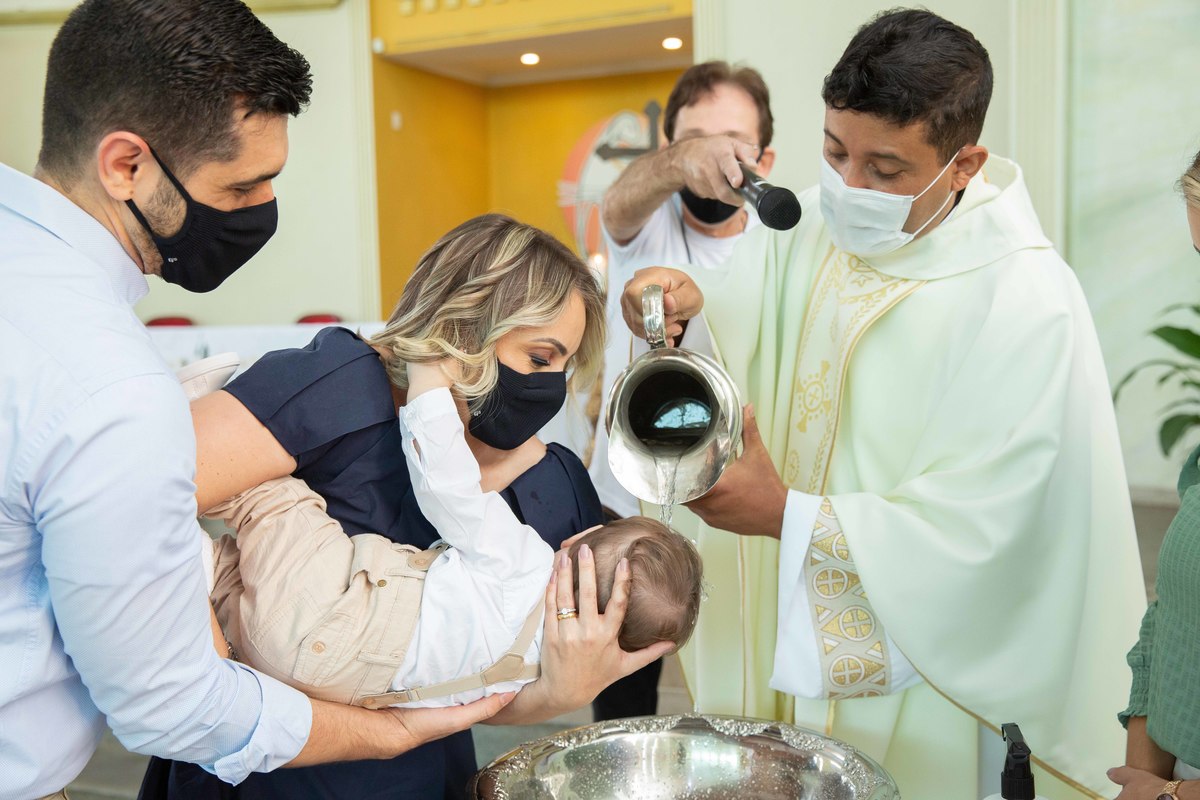 Agua pia batismal sendo derramada cabeça do menino padre