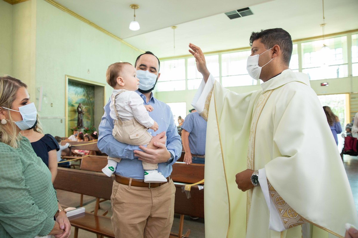 Menino olhando para o padre no colo daopai batizado oracao do padre benção