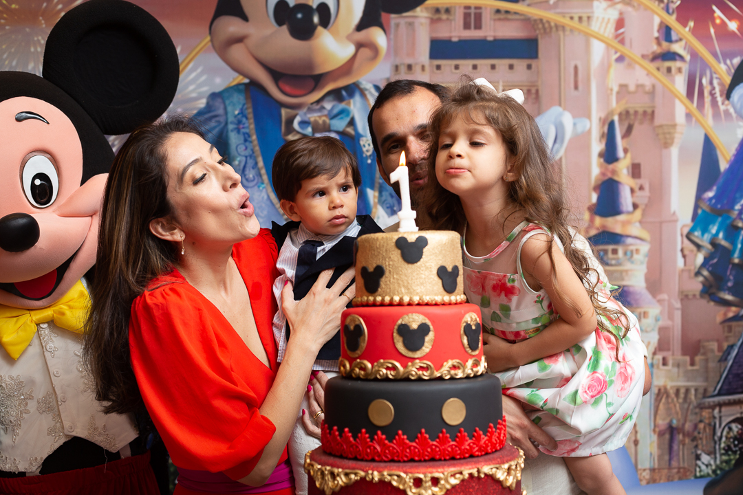 Pais com seus filhos no colo- festa de aniversário tema da Disney