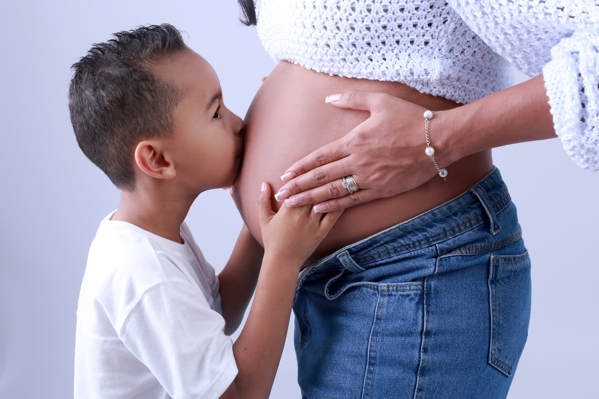 Irmão dando beijo na barriga da mamãe
