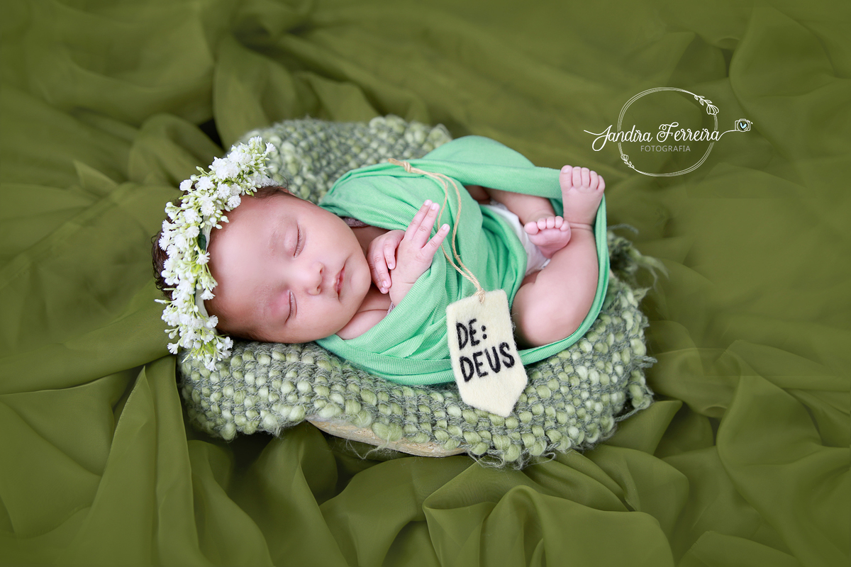 bebê dormindo  durante ensaio newborn em estúdio em São Paulo com cenário verde e coroa de flores.