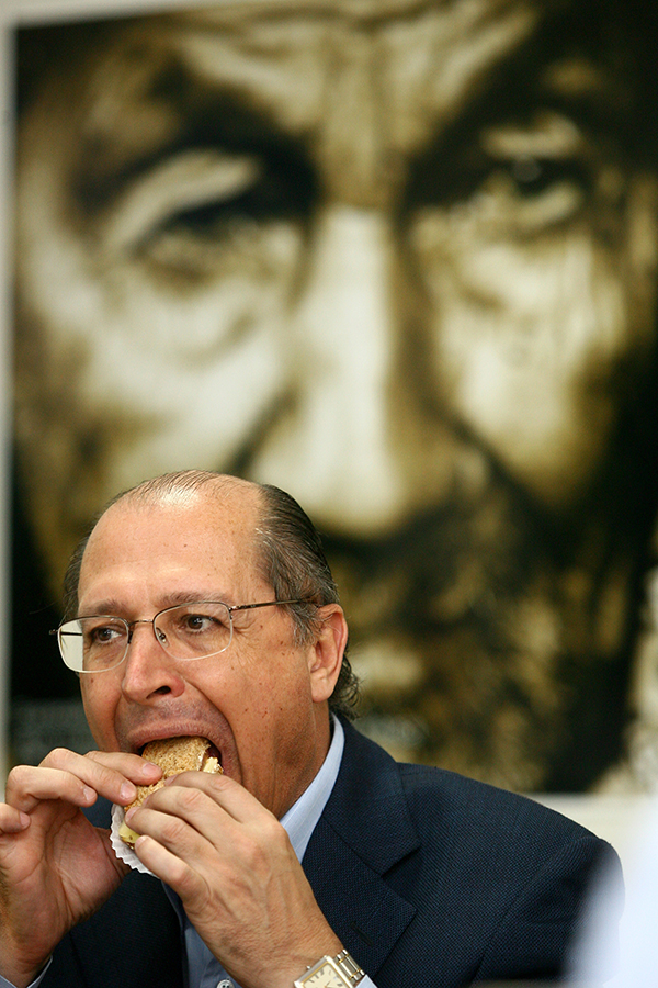 Governador Geraldo Alckmin comendo pão com a boca aberta