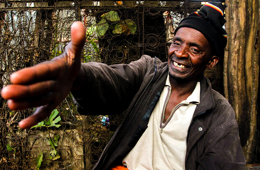 Homem africano sorri e faz cumprimento com a mão