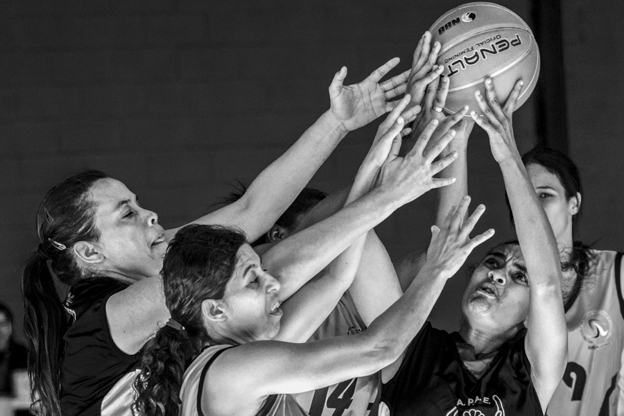 Mulheres disputam a bola de basquete durante partida
