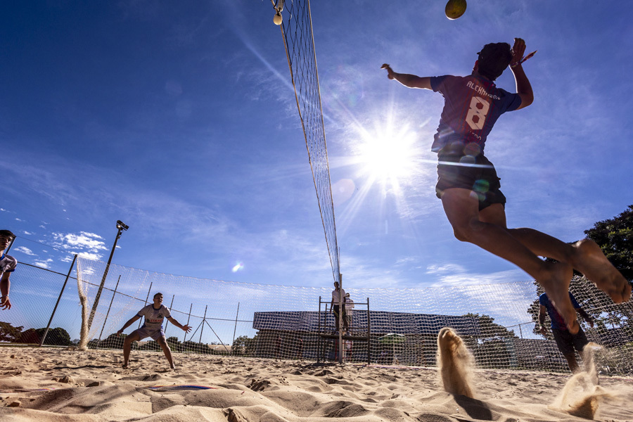 jogador salta para cortar a bola em quadra de volei de areia