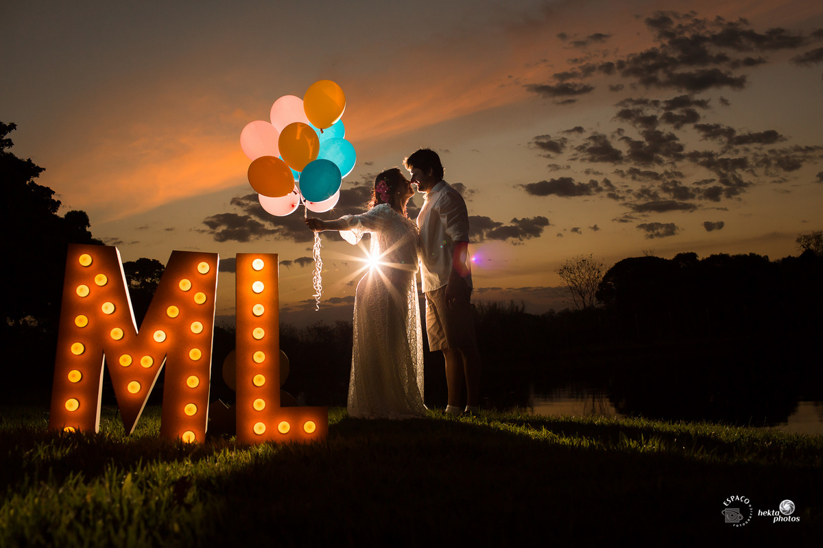 penumbra do casal no por do sol com letras, luzes e balões