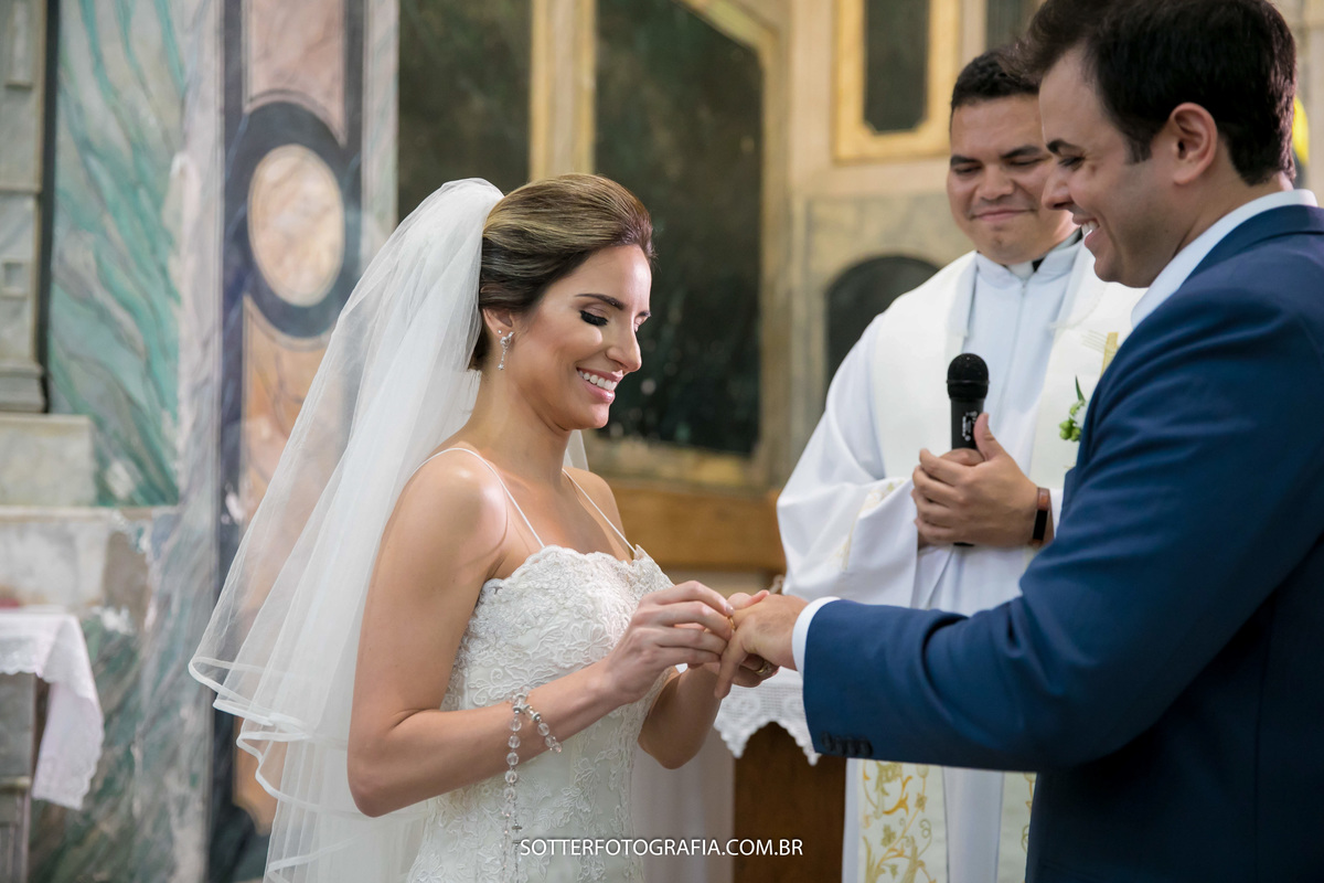 noiva colocando a aliança no noivo e sorrindo 