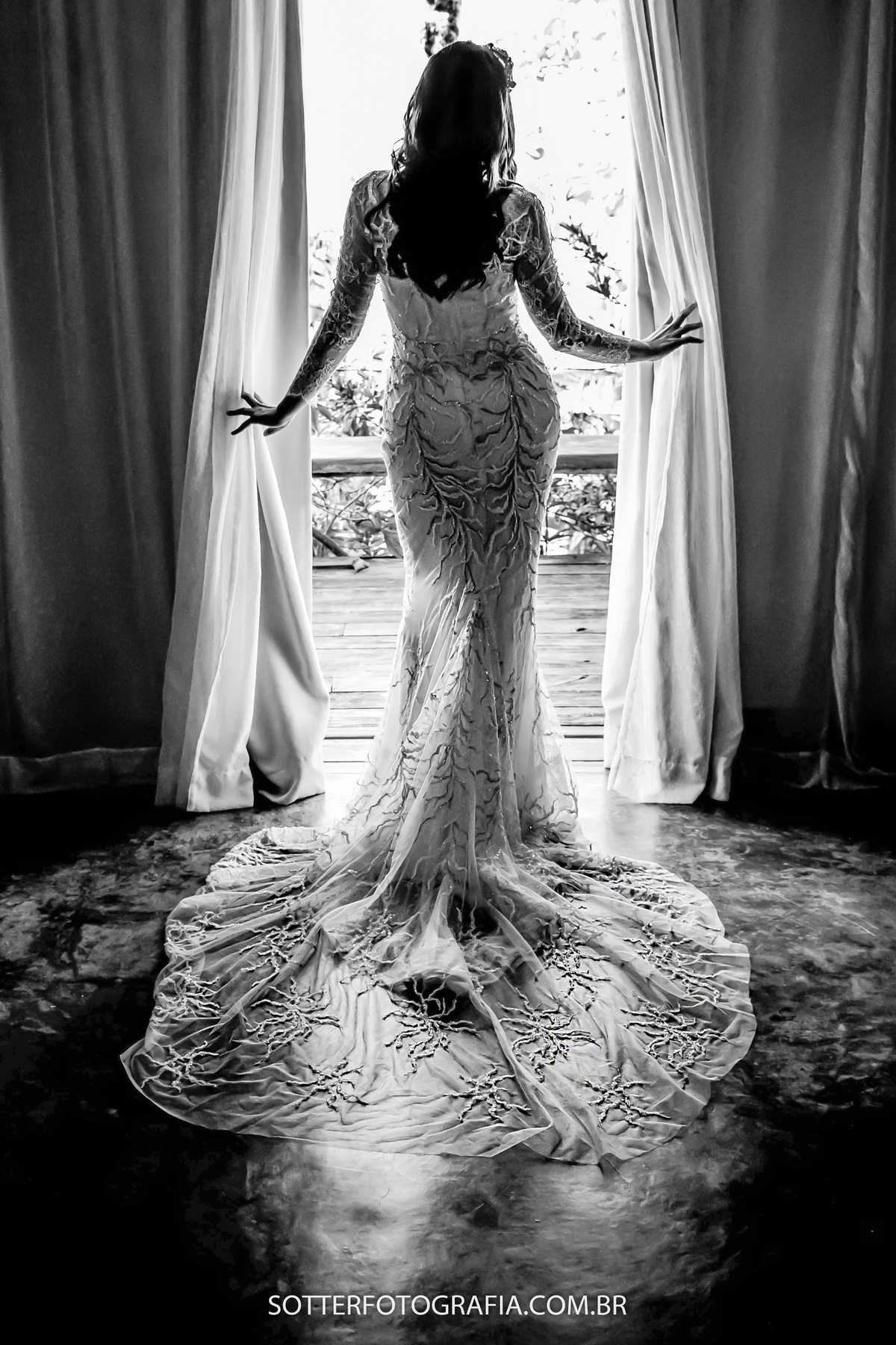 noiva abrindo a janela entrando uma luz linda que faz o contorno do seu corpo junto com os detalhes do vestido