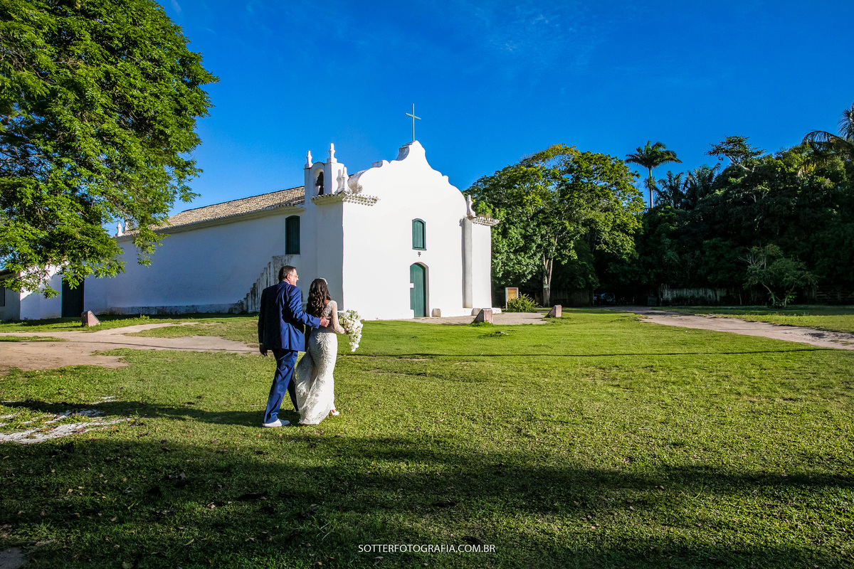 noiva ao lado do pai atravessando o quadrado em trancoso, passando pela frente da igrejinha 