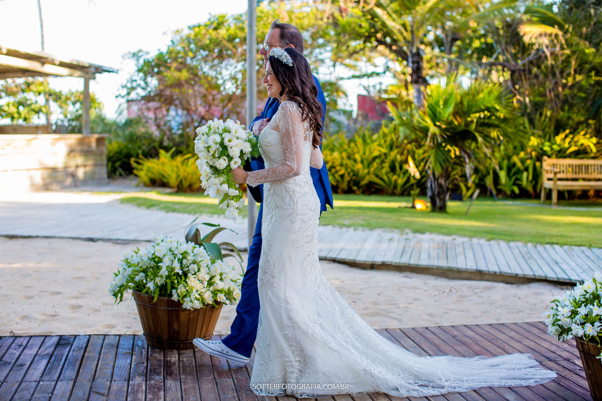 noiva de lado caminhando com o pai em direção ao noivo