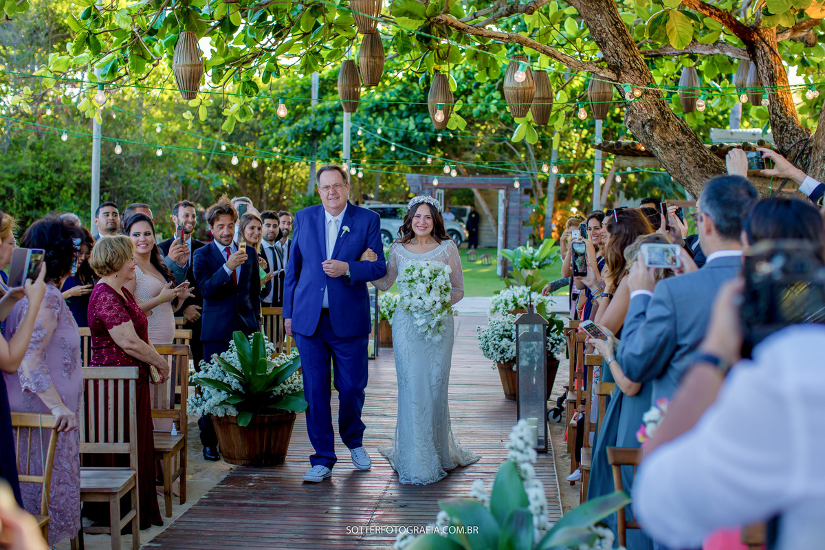 noiva entrando no casamento, passando por baixo de uma arvore linda