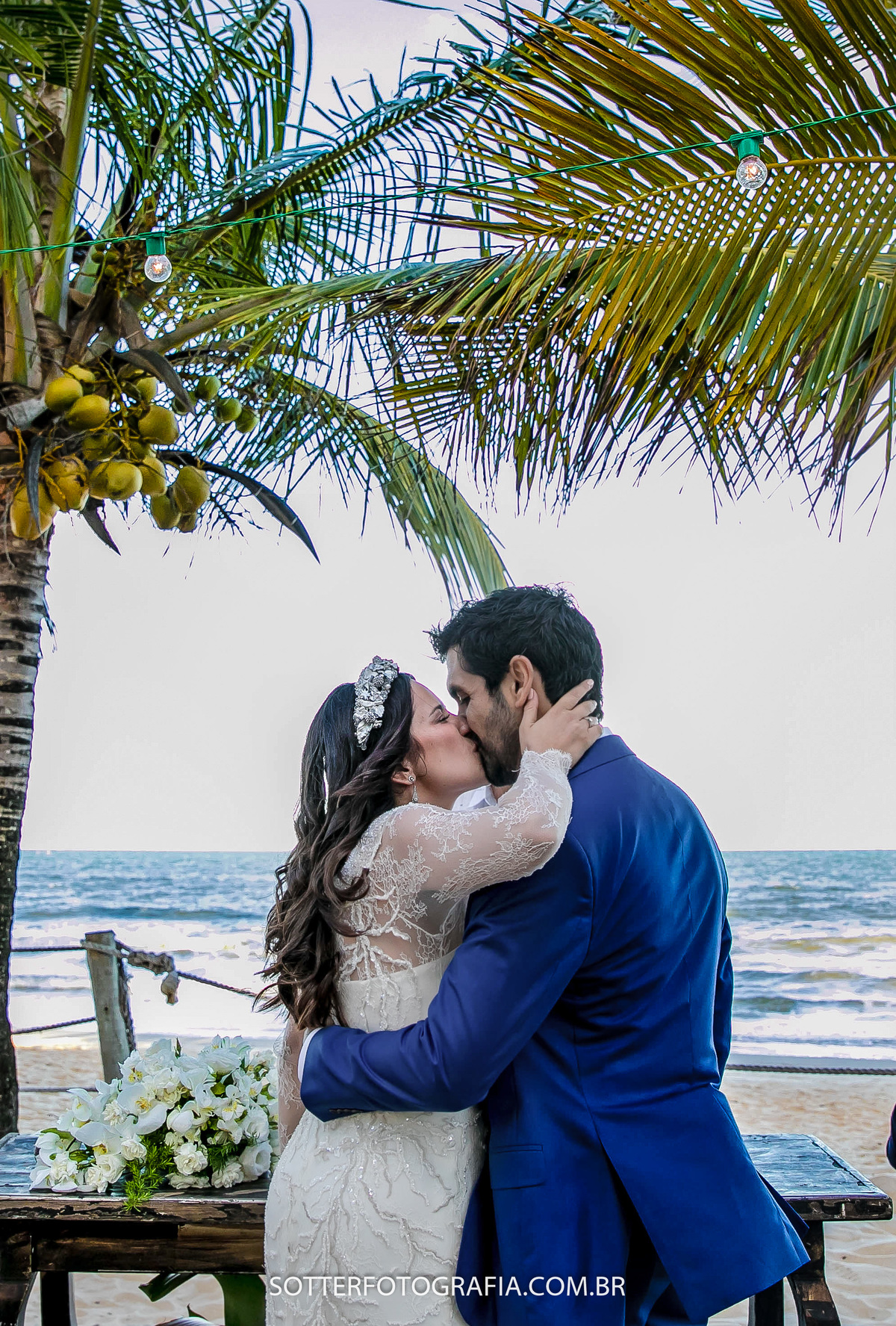 o momento do beijo, a noiva segura o noivo pela cabeça e o beija, ao fundo o mar de trancoso 