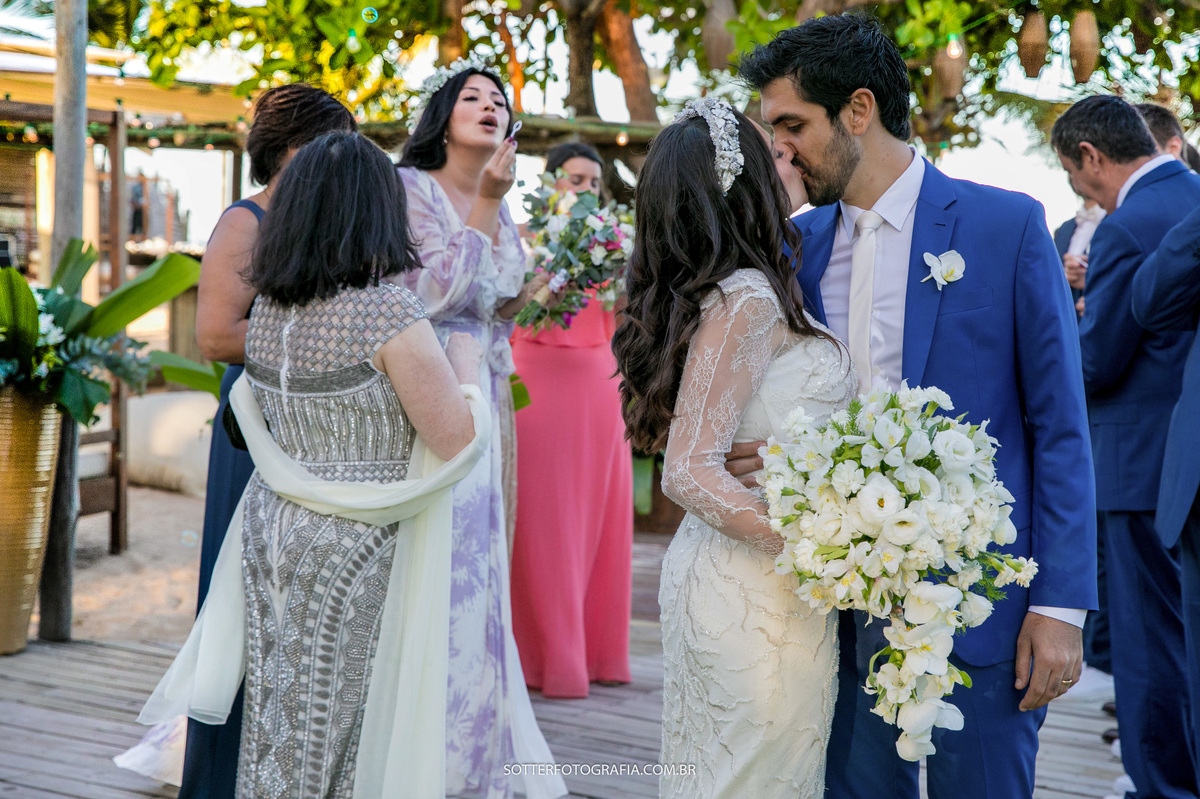 noivos se beijando assim que terminou a cerimônia enquanto pessoas passar por perto