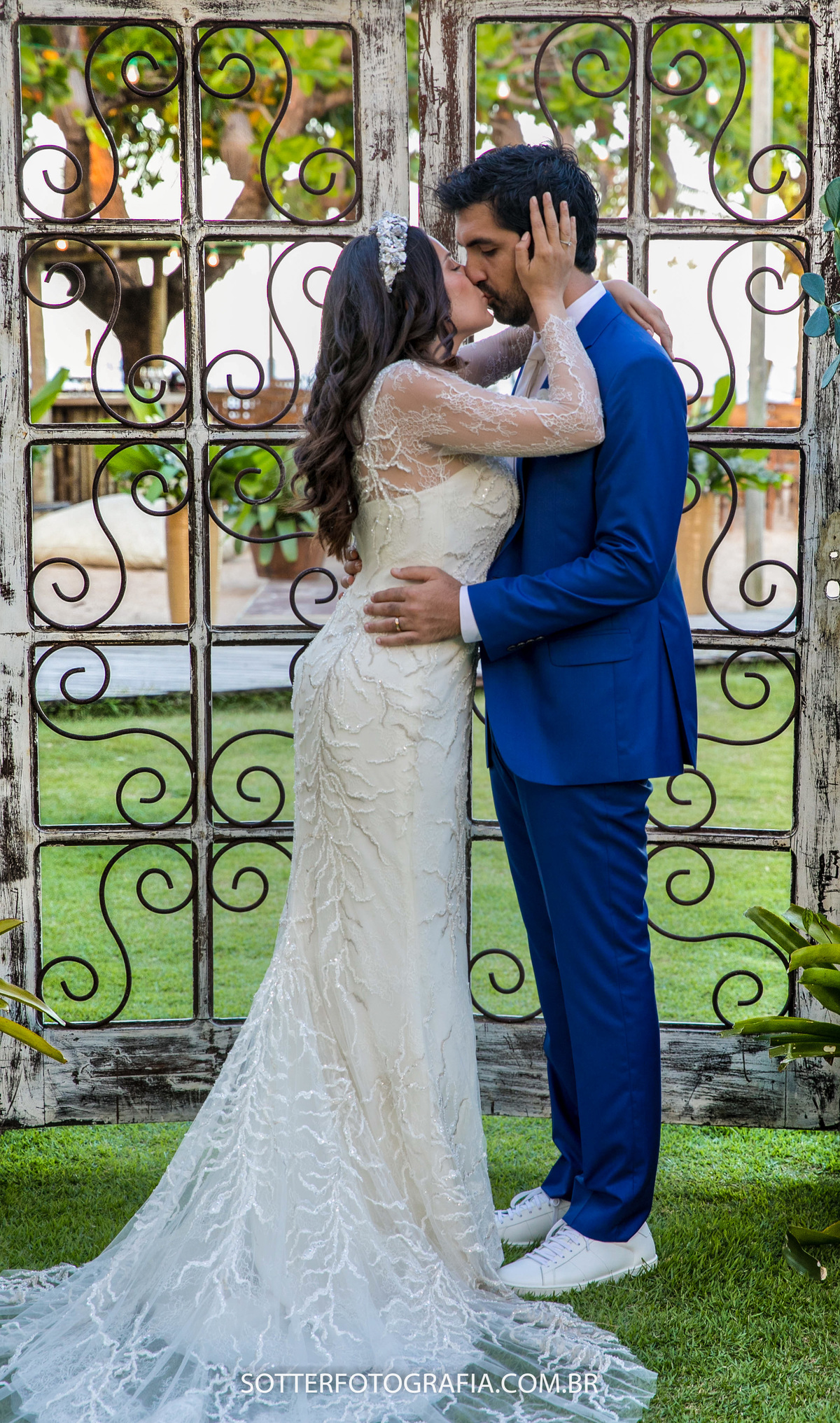em trancoso aconteceu esse casamento lindo nessa imagem os noivos estão se abraçando em frente a um portal lindo feito de madeira e ferro para a passagem da noiva foto feita por sotter fotografia fotografo em trancoso bahia 