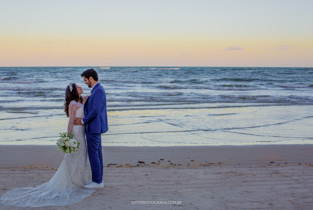 o céu laranja fez uma linda composição nesta imagem onde os noivos estão de frente um para o outro se olhando 