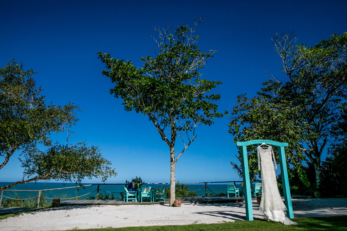 vestido da noiva pendurado em uma porta na pousada segredos de trancoso, ao fundo o mar e muitas árvores
