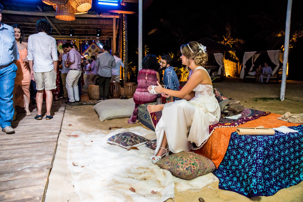 NOIVA TIRANDO AREIA DE PRAIA DA SANDÁLIA DURANTE O SEU CASAMENTO EM TRANCOSO QUE A SOTTER FOTOGRAFIA REGISTROU