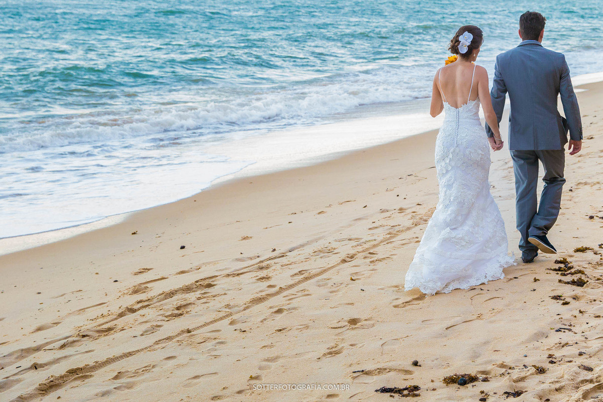 
NOIVOS CAMINHANDO NA PRAIA APÓS A CERIMONIA RELIGIOSA EM ARRAIAL DAJUDA FOTOGRAFO DE CASAMENTO EM TRANCOSO 