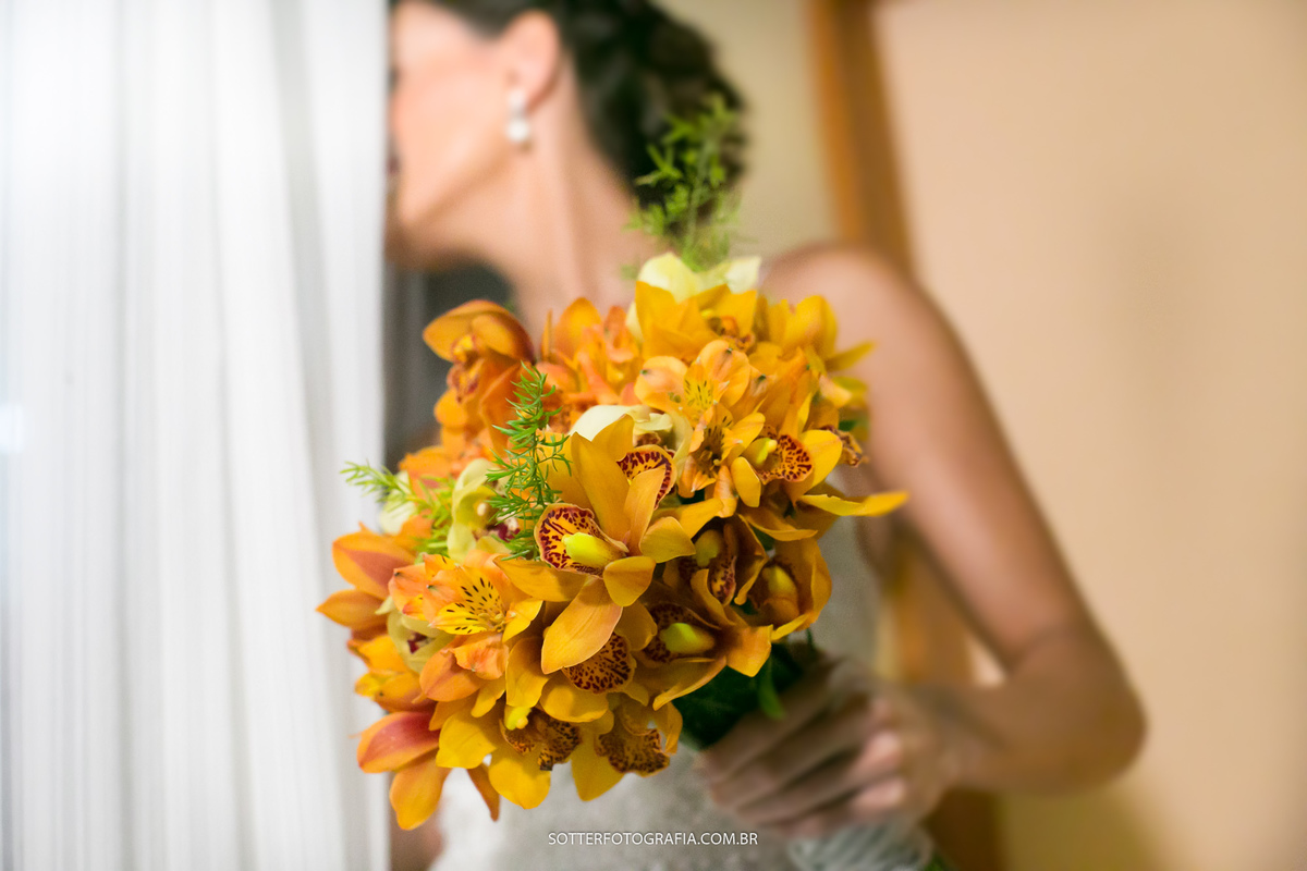 Noiva segurando o buquê enquanto olha pela janela o inicio da cerimonia, momento registrado por sotter fotografia em arraial