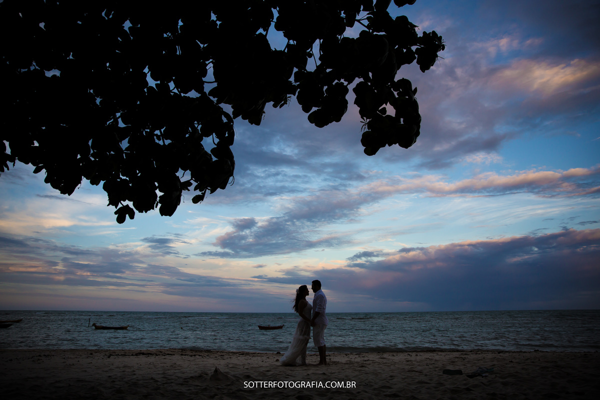 silhueta na praia com o mar e folhas de arvores cores lindas do por do sol deixando a imagem ainda mais bonita pelas lentes da sotter fotografia 