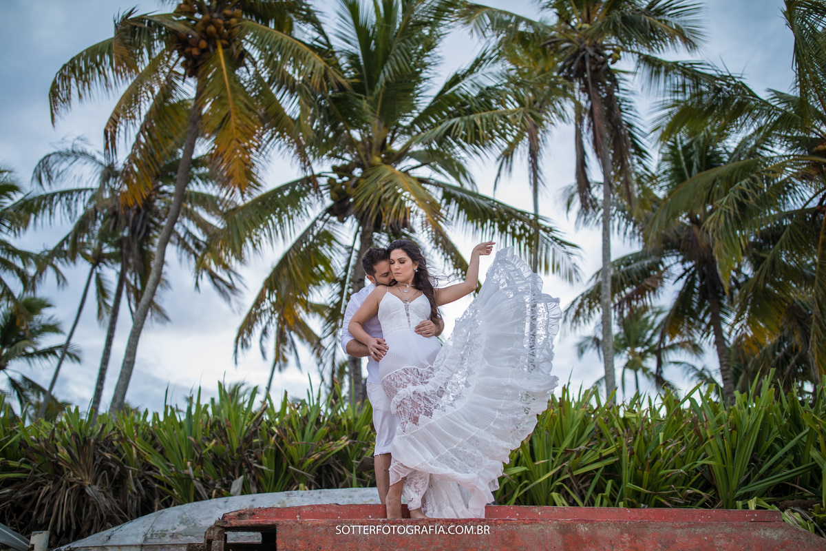 noivos encima de um barco e atras varios coqueiros deixando a paisagem ainda mais bonita para o registro da foto pela equipe sotter fotografia 