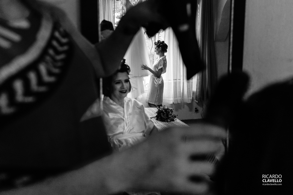 Mãe da noiva se arrumando, enquanto a noiva contempla o vestido na janela,- Fotografia de Casamento RJ - Fotografia de Casamento Niterói - Fotógrafo de Casamento RJ - Fotografia de Casamento JF - Fotografo Casamento - Melhores fotos de casamento