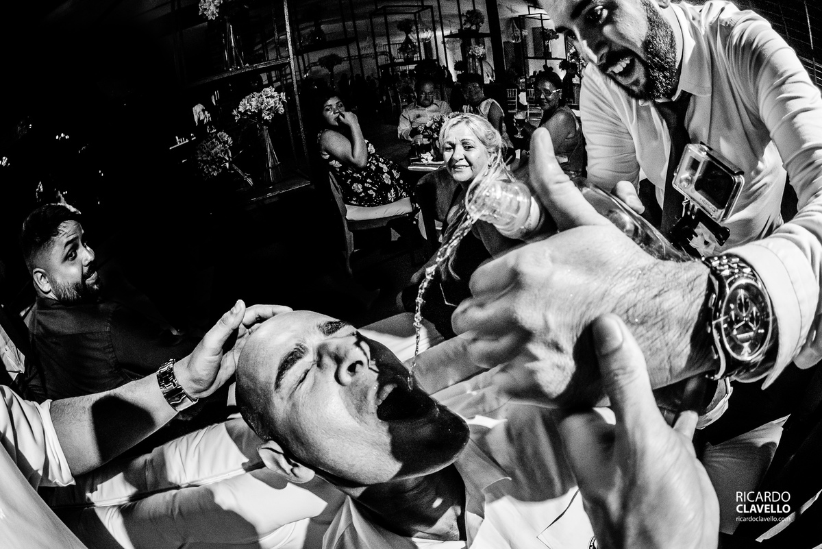 convidado bebendo whisky direto do gargalo enquanto uma mão faz a garrafa derramar - Fotografia de Casamento RJ - Fotografia de Casamento Niterói - Fotógrafo de Casamento RJ - Fotografia de Casamento JF - Fotografo Casamento - Melhores fotos de casamento