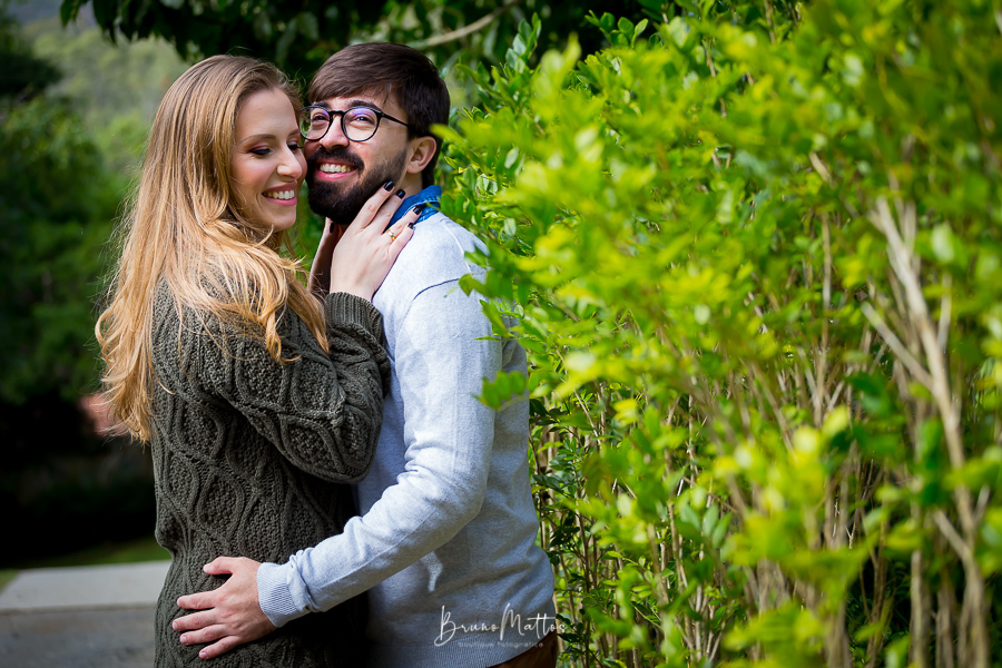 casal abraçado encostado na vegetação
