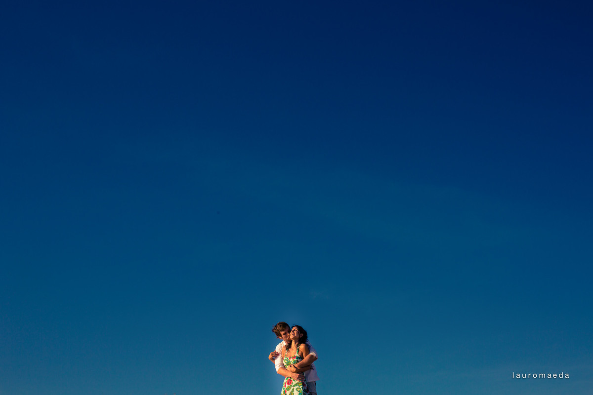 Casal abraçado com céu azul como pano de fundo