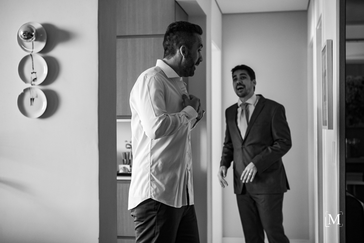 noivo abotoando a camisa e seu amigo