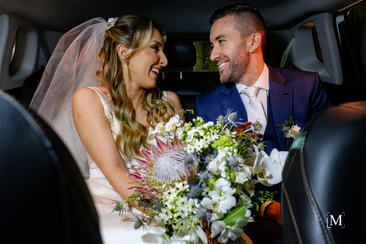noivos no carro sorrindo um para o outro