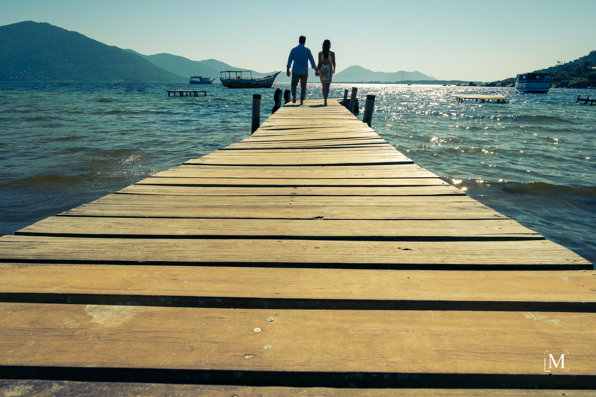 casal de noivos caminhando no trapiche na lagoa da conceição