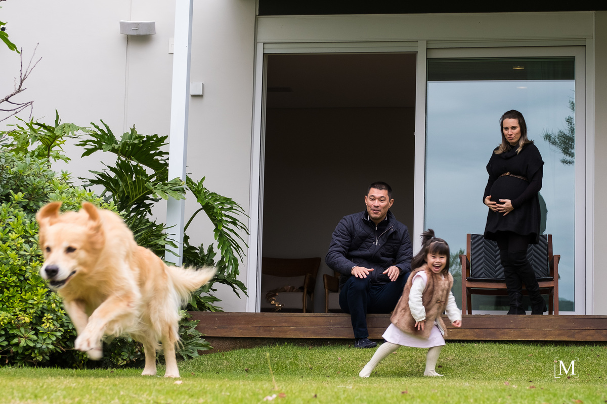 cão correndo e menina olhando com o pais