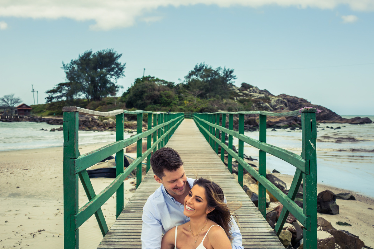 Noivos sentados na passarela da Praia da Armação sul da ilha de santa catarina