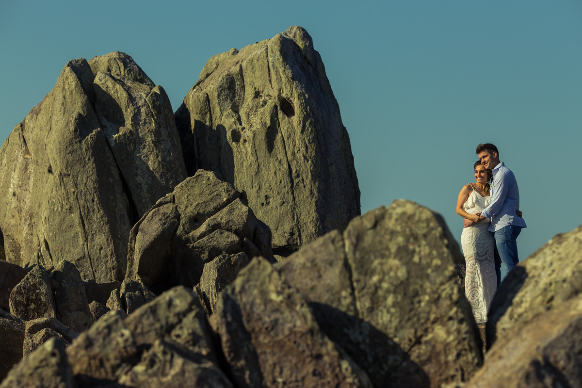 casal abraçado nas pedras da praia da armação em florianópolis