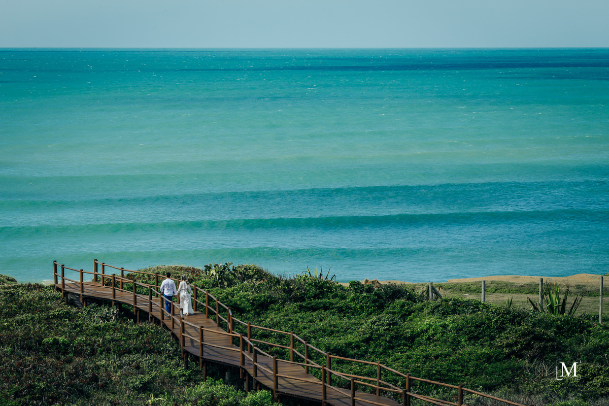 Visual da praia do Morro das Pedras com casal na passarela
