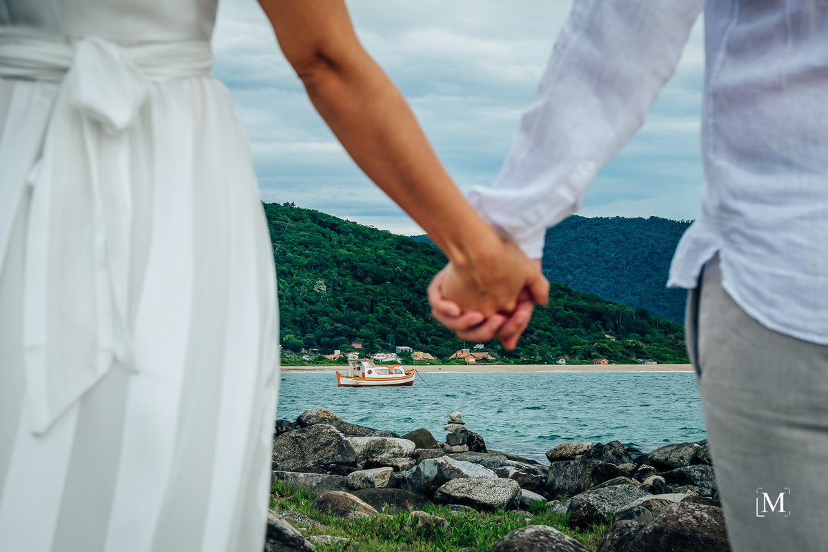 casal de mãos dadas e barco no fundo