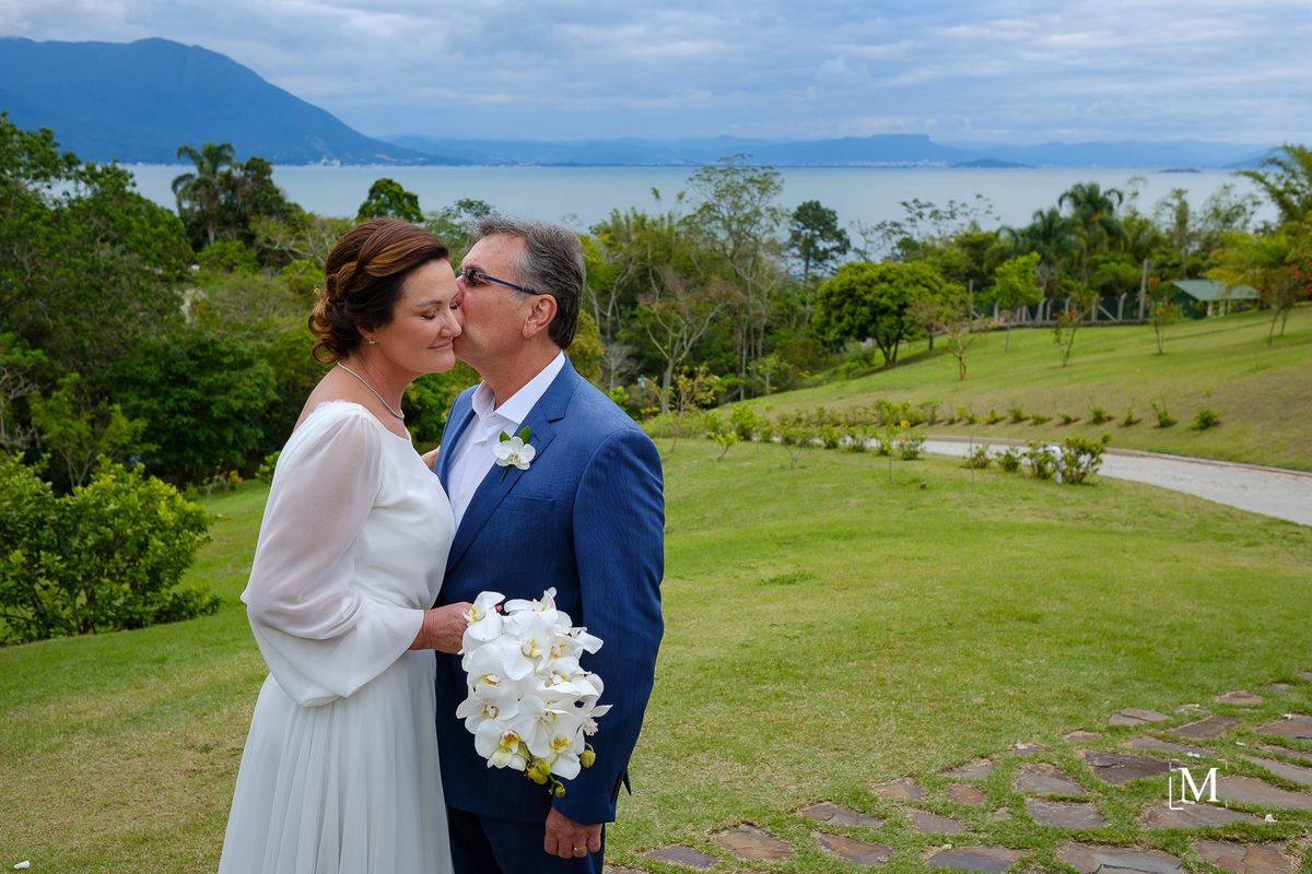 noivo beijando a noiva com o mar de fundo