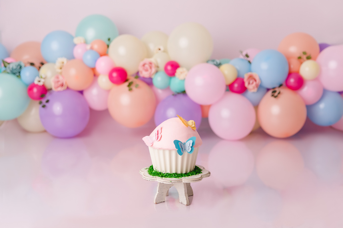 ensaio smash the cake jardim encantado bebe infantil primeiro aninho cadeirinha balões coloridos flores sorrindo roupinha renda e tiara de flores cenário e bolo com borboletas