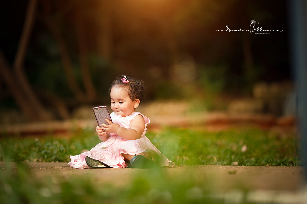 ensaio infantil com a Isabella vendo video no celular