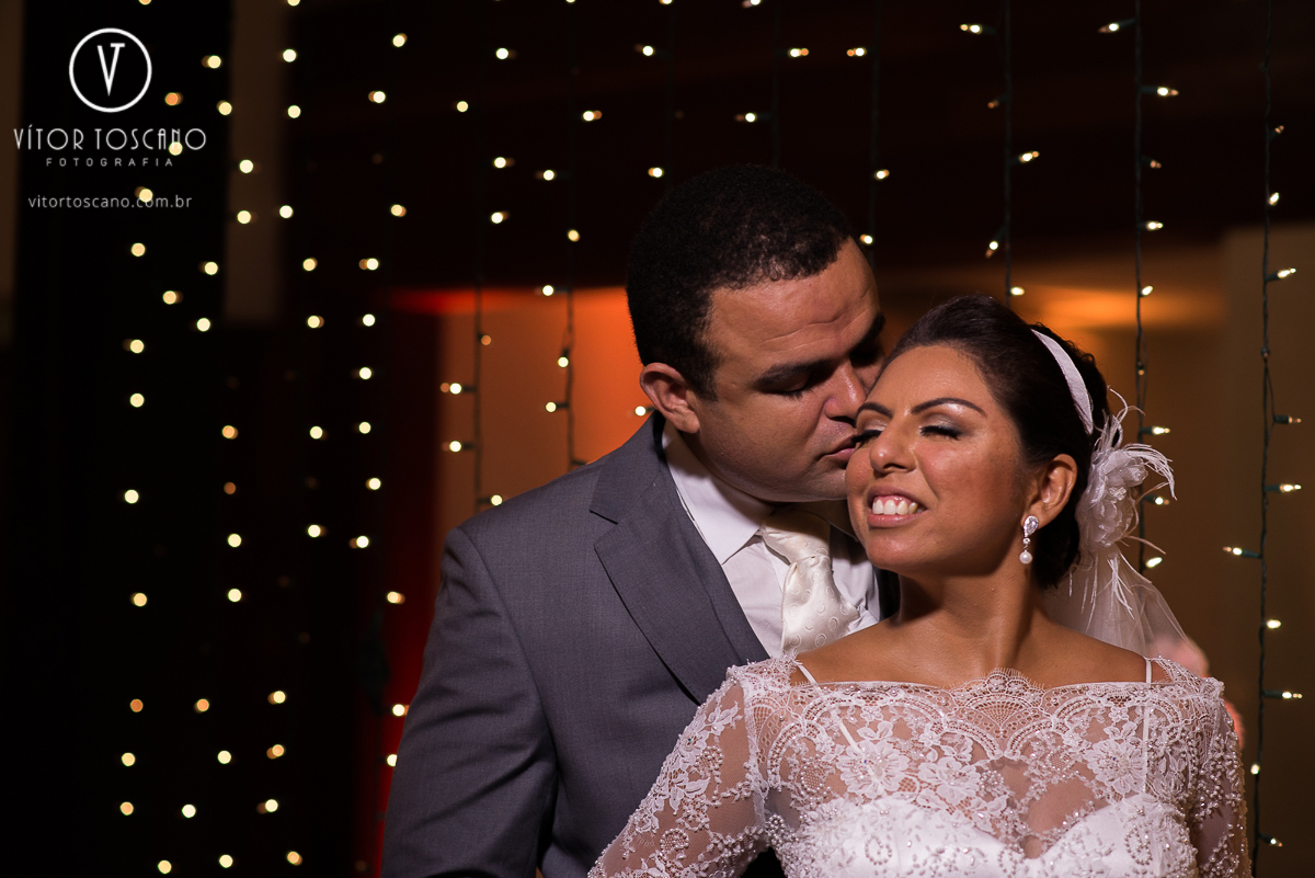 Noivo beijando o canto do olho da noiva no casamento de Jucielly e Auderi, em Natal-RN.
