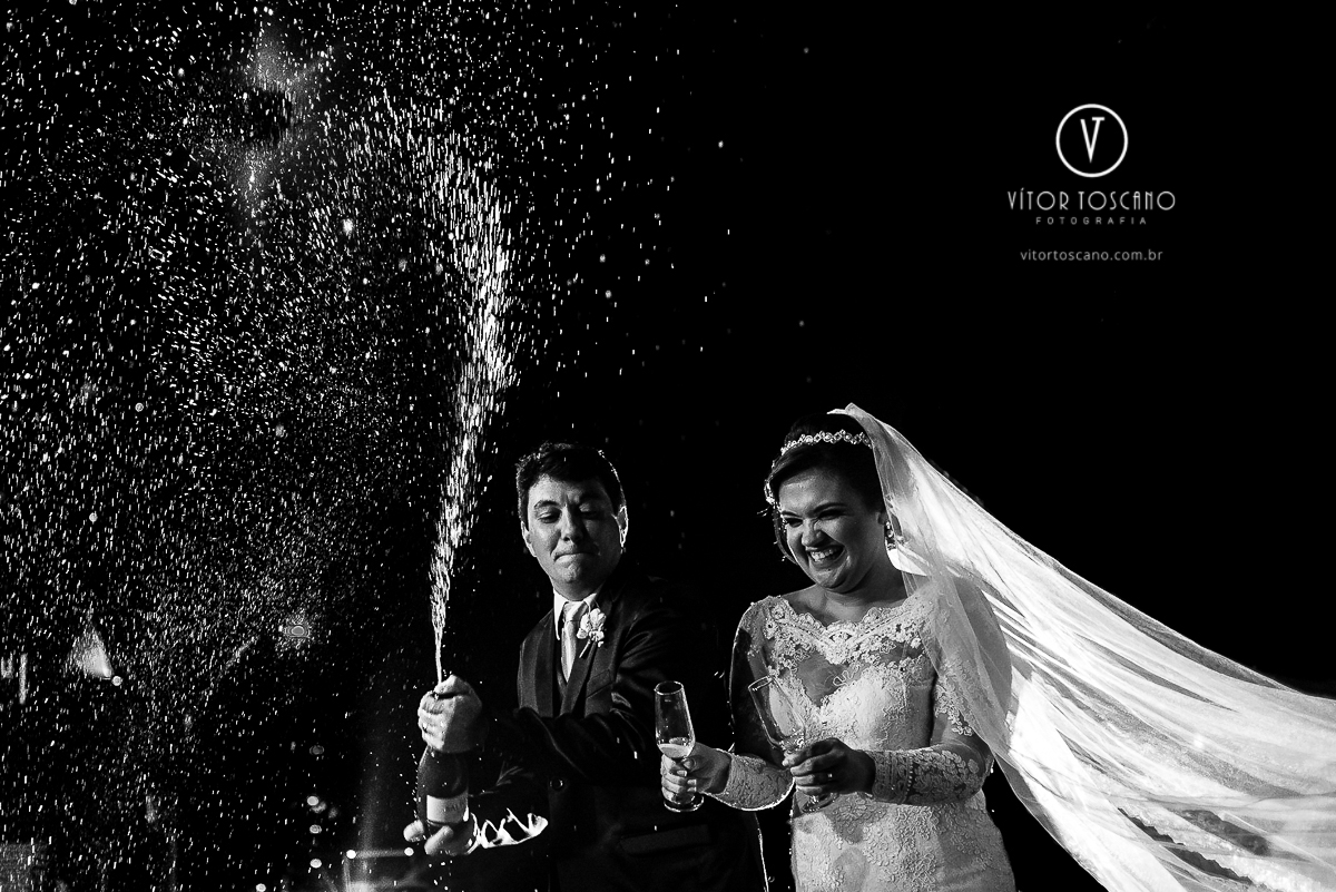 Noivos estourando o brinde no casamento de Flavia e Tulio, em Natal-RN.