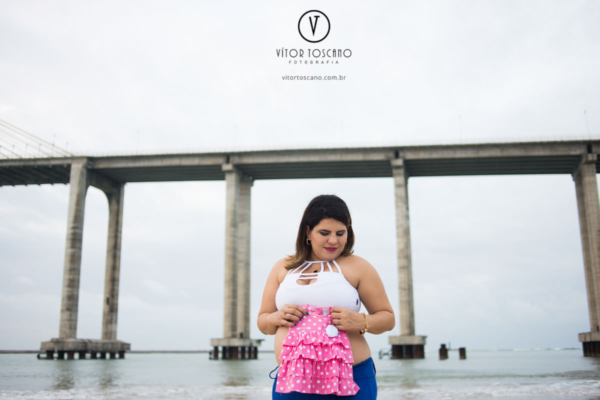Mãe segurando o vestido da bebê no ensaio de gestante, em Natal-RN na praia do y.