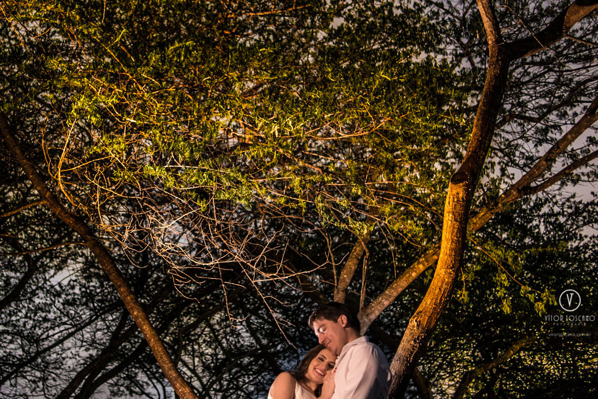 Casal abraçado sob as árvores iluminadas no ensaio de casal de Andreza e Thales em Macaiba - RN