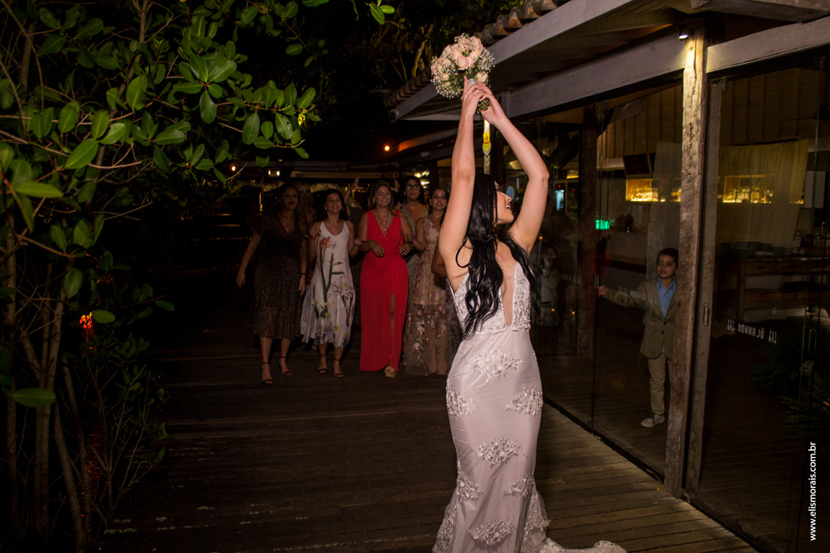 Foto da noiva jogando o buquê no casamento no restaurante Dona Jô no Porto da Barra em Búzios