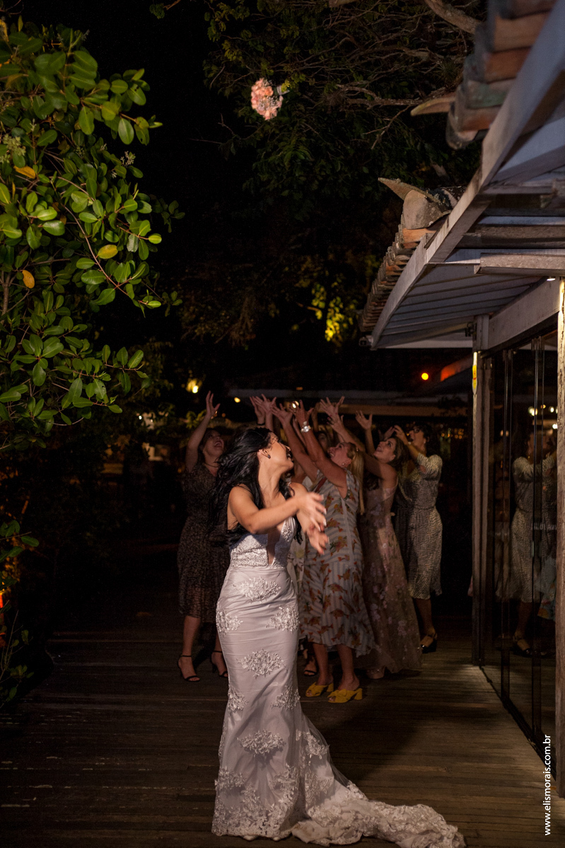 Foto da noiva jogando o buquê no casamento no restaurante Dona Jô no Porto da Barra em Búzios
