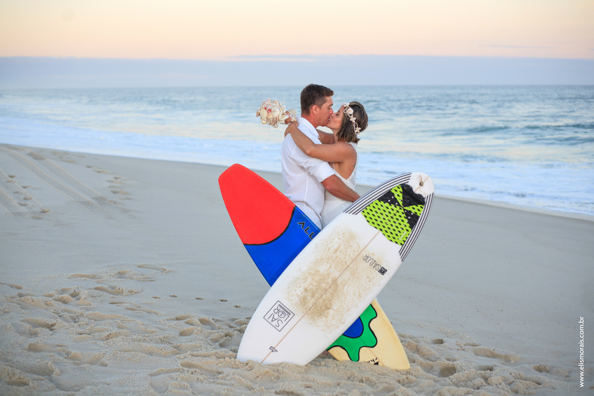 fotos do ensaio fotográfico dos noivos com pranchas de surf ao por do sol no elopement wedding na Praia de Itaúna em Saquarema - RJ. 