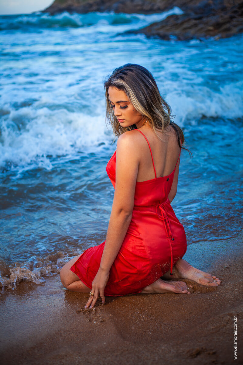 ensaio fotográfico feminino com vestido vermelho dentro da água na praia